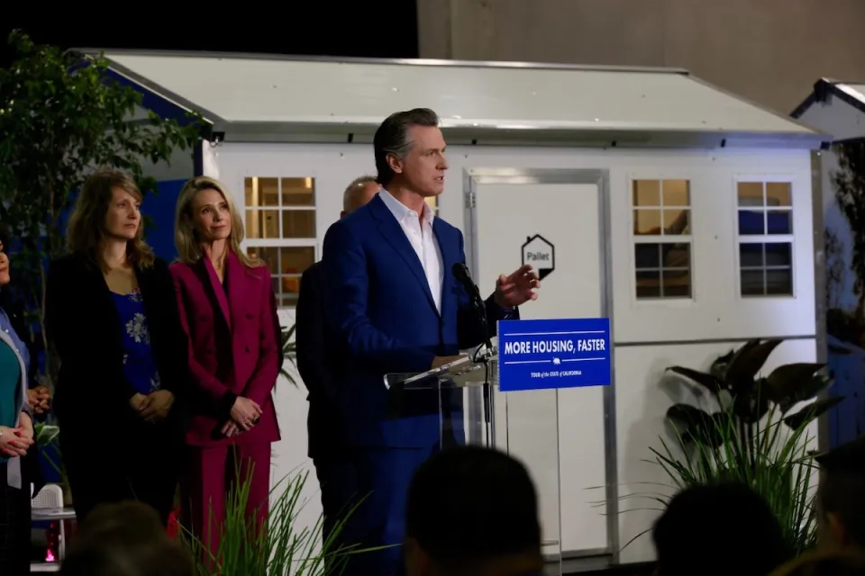California Governor Gavin Newsom announcing funding for tiny home shelter project in front of quick-build tiny home shelter unit.